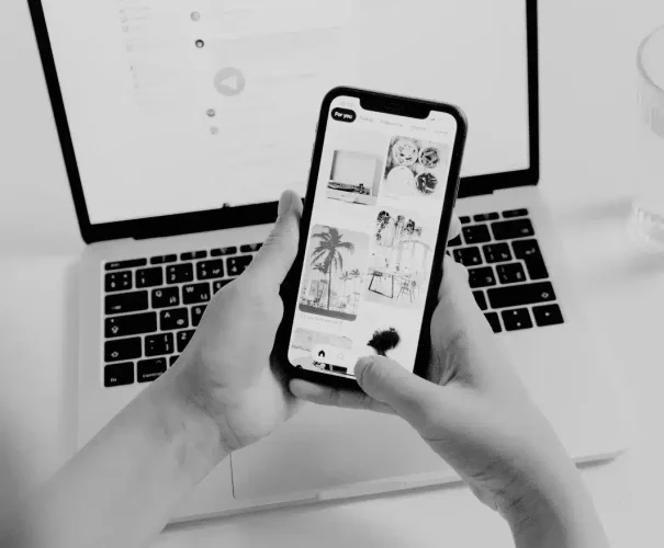 Social media feed on smartphone in front of laptop // Közösségi média hírfolyam okostelefonon, laptop előtt